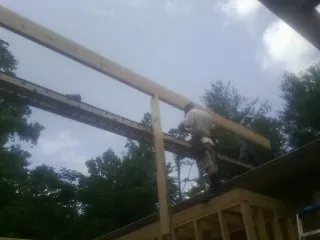 Carpenter setting a ridge beam over a new addition frame in Springfield