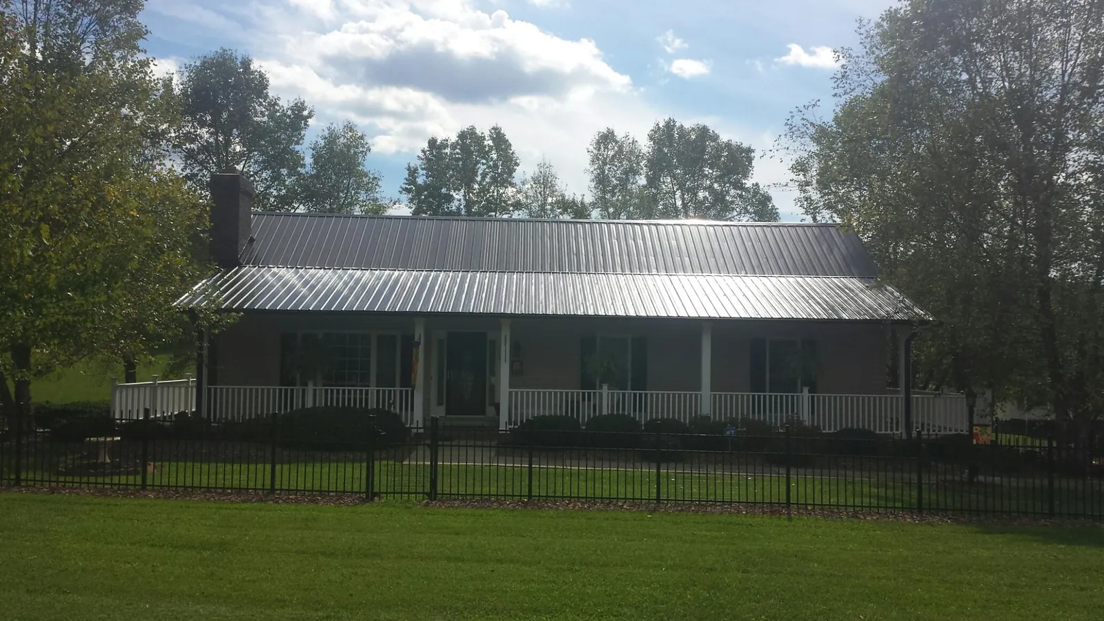 Gray metal roof on a brick ranch with a full width front porch — Gutter Guard Installation work by our crew in Springfield